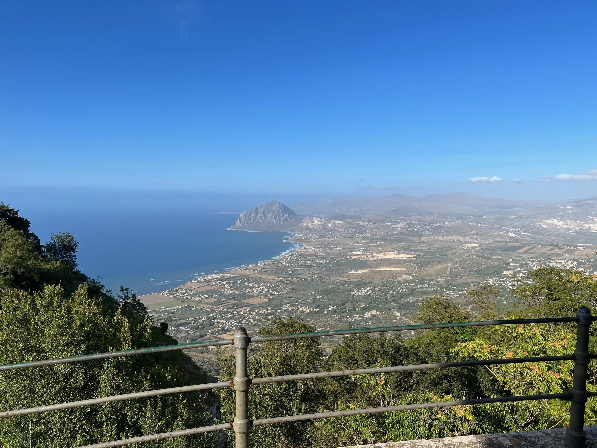 Vy över en kust med hav, berg och fält, sett från en utsiktsplats med säkerhetsräcke i Erice, Trapani i Sicilien.