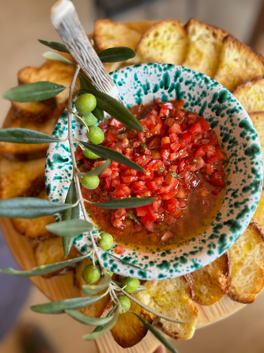 Skål med tomatsalsa omgivet av skivat bröd och olivkvistar i Sicilien.