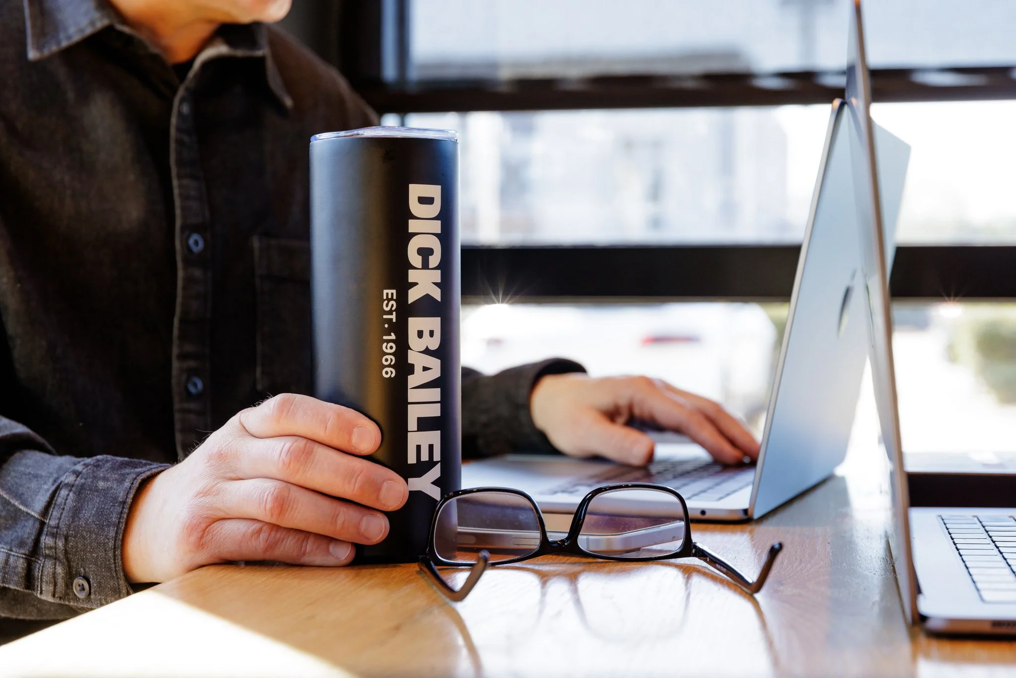Writing legal insights at desk with Dick Bailey Service coffee cup