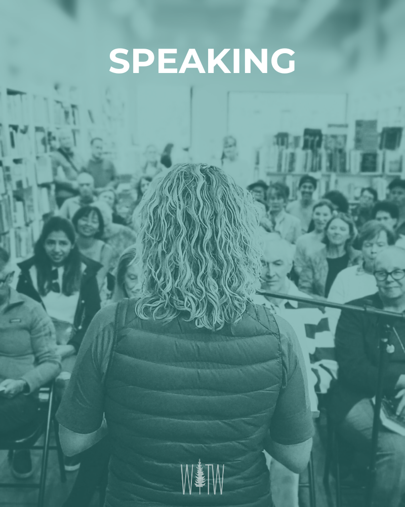 Woman speaking in front of an audience in a library setting.