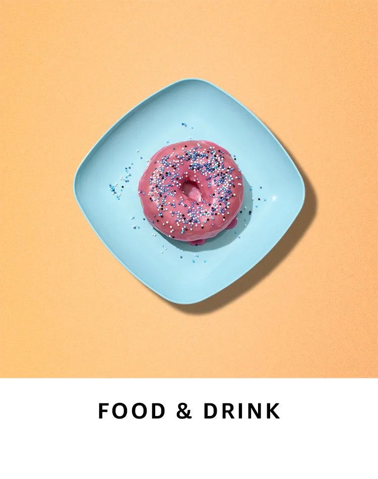 Pink frosted donut with colorful sprinkles on a blue square plate, against a peach background.