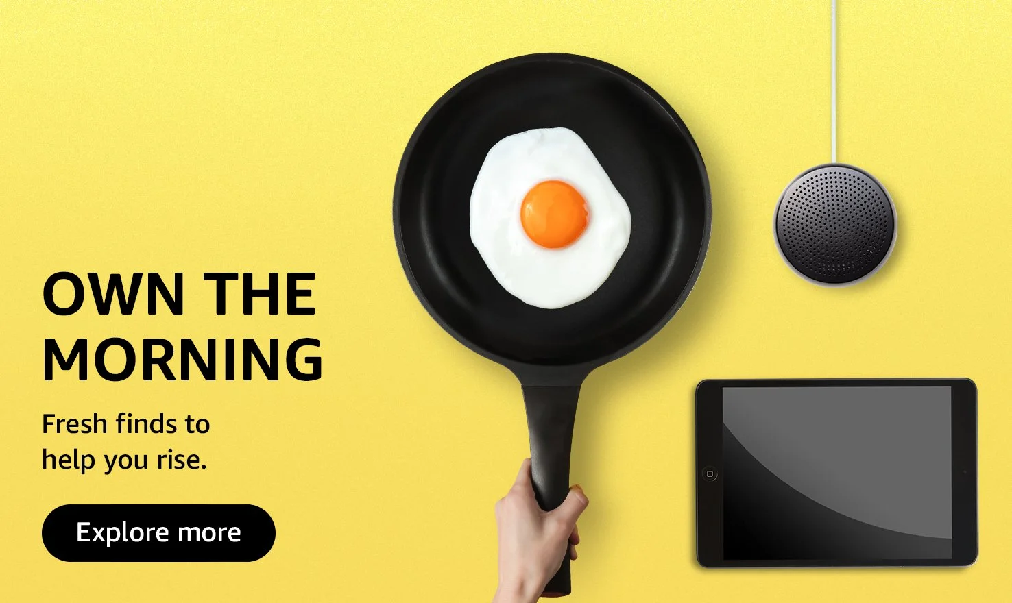 A frying pan with a cooked egg on a yellow background, a smart speaker, and a tablet, accompanied by text that says 'Own the Morning. Fresh finds to help you rise.' and a button labeled 'Explore more'.