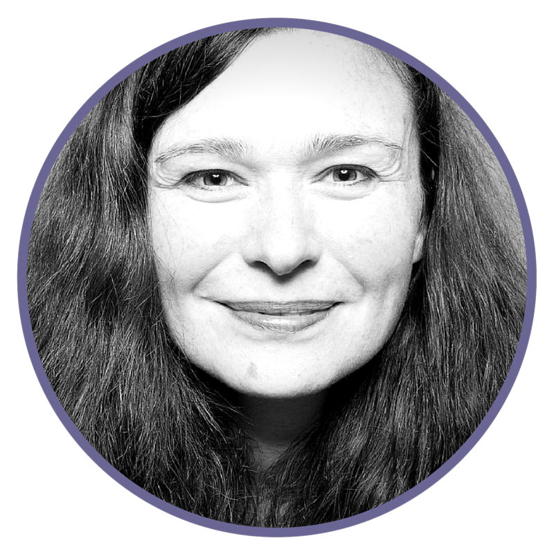 Black and white close-up portrait of a smiling woman with long, wavy hair, looking directly at the camera.