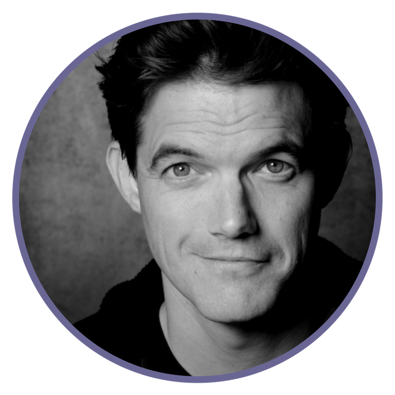 Black and white portrait of a man with dark, slightly tousled hair, smiling subtly, against a textured background.