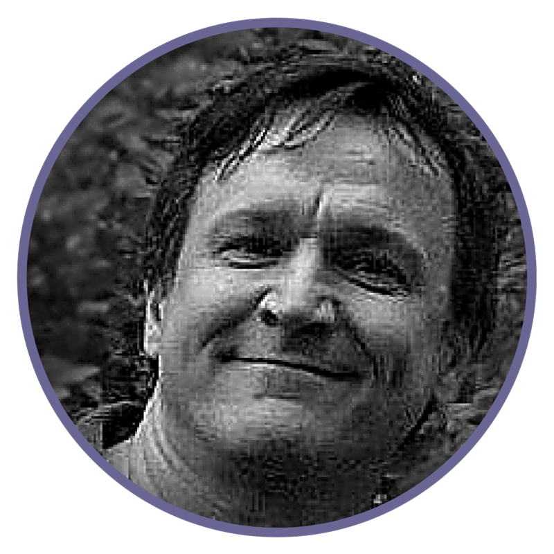 A black and white photo of a smiling woman with short, curly hair outdoors.