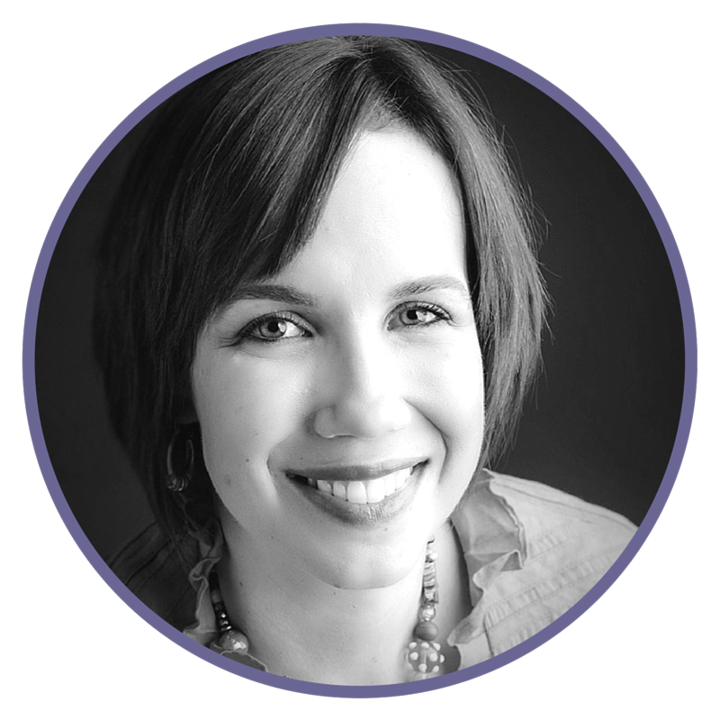 Black and white portrait of a woman with short hair smiling, wearing earrings and a necklace.