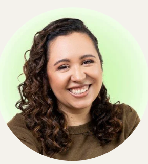 Smiling woman with glasses and earrings in an indoor setting.