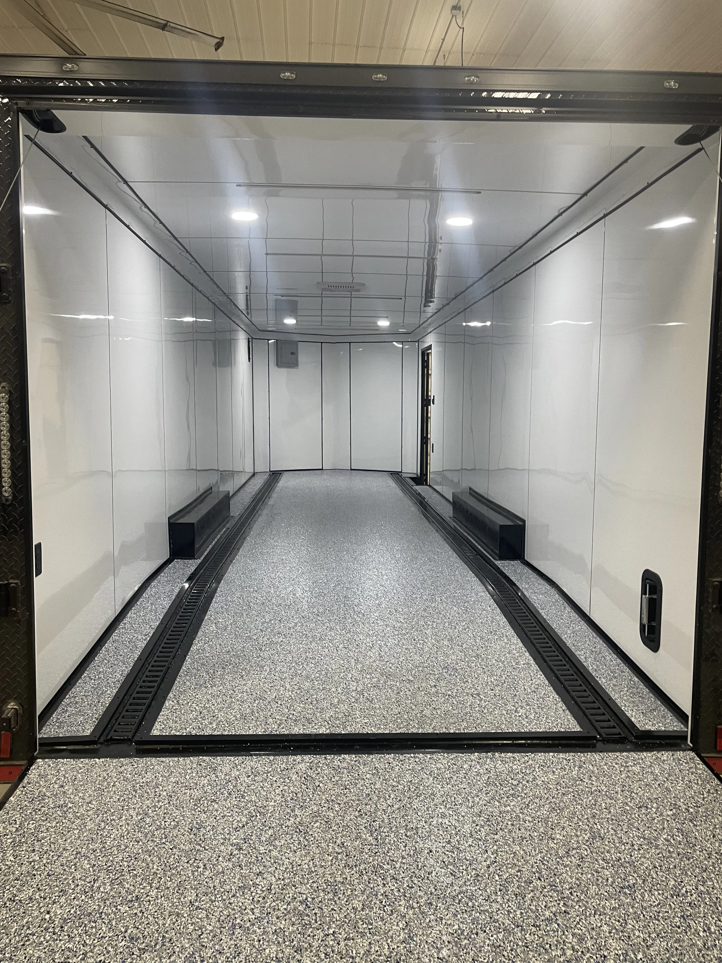 Empty storage trailer with white interior walls, gray carpeted floor, and black vents.