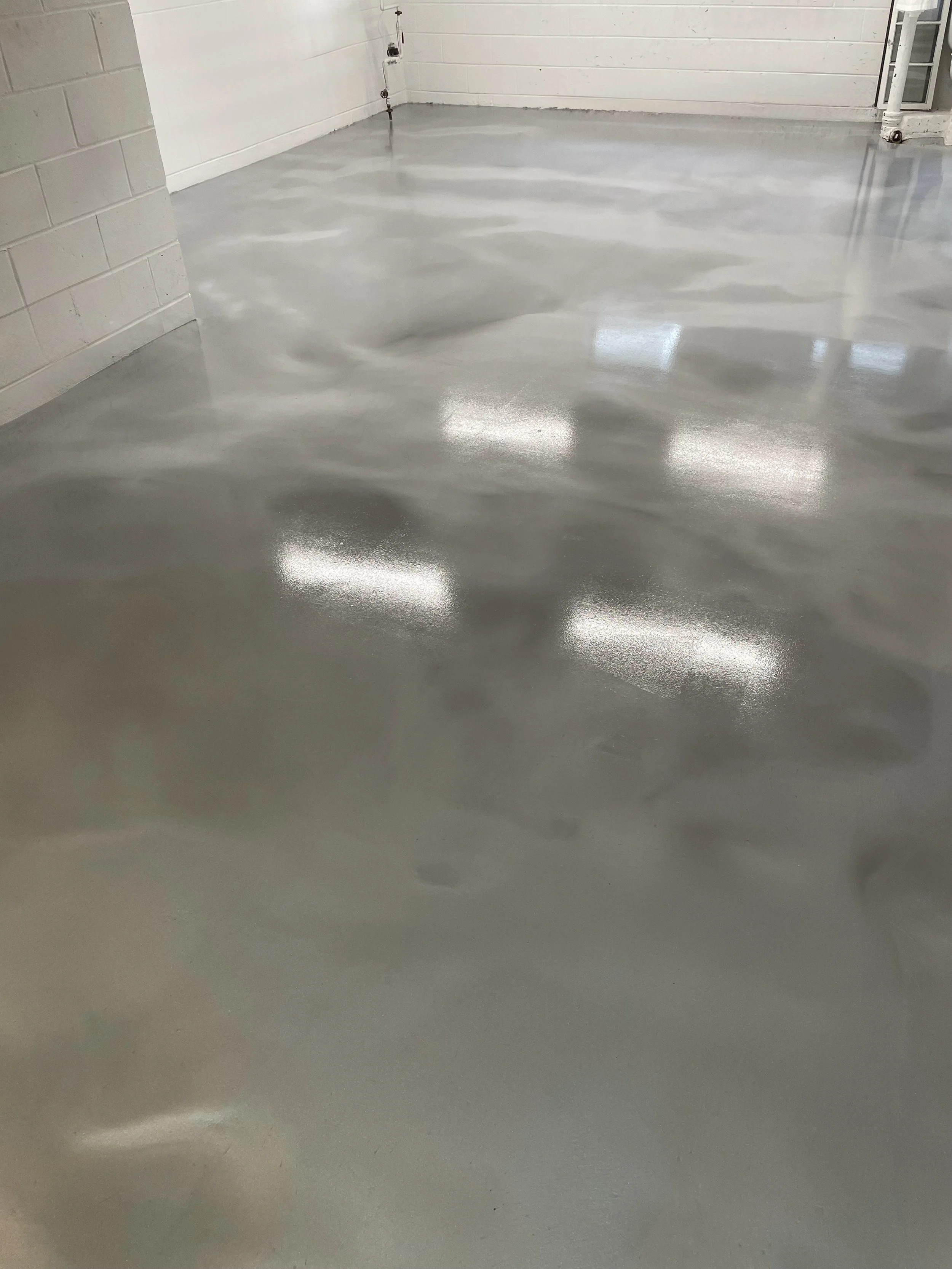 Polished concrete floor in a room with white walls and a window.