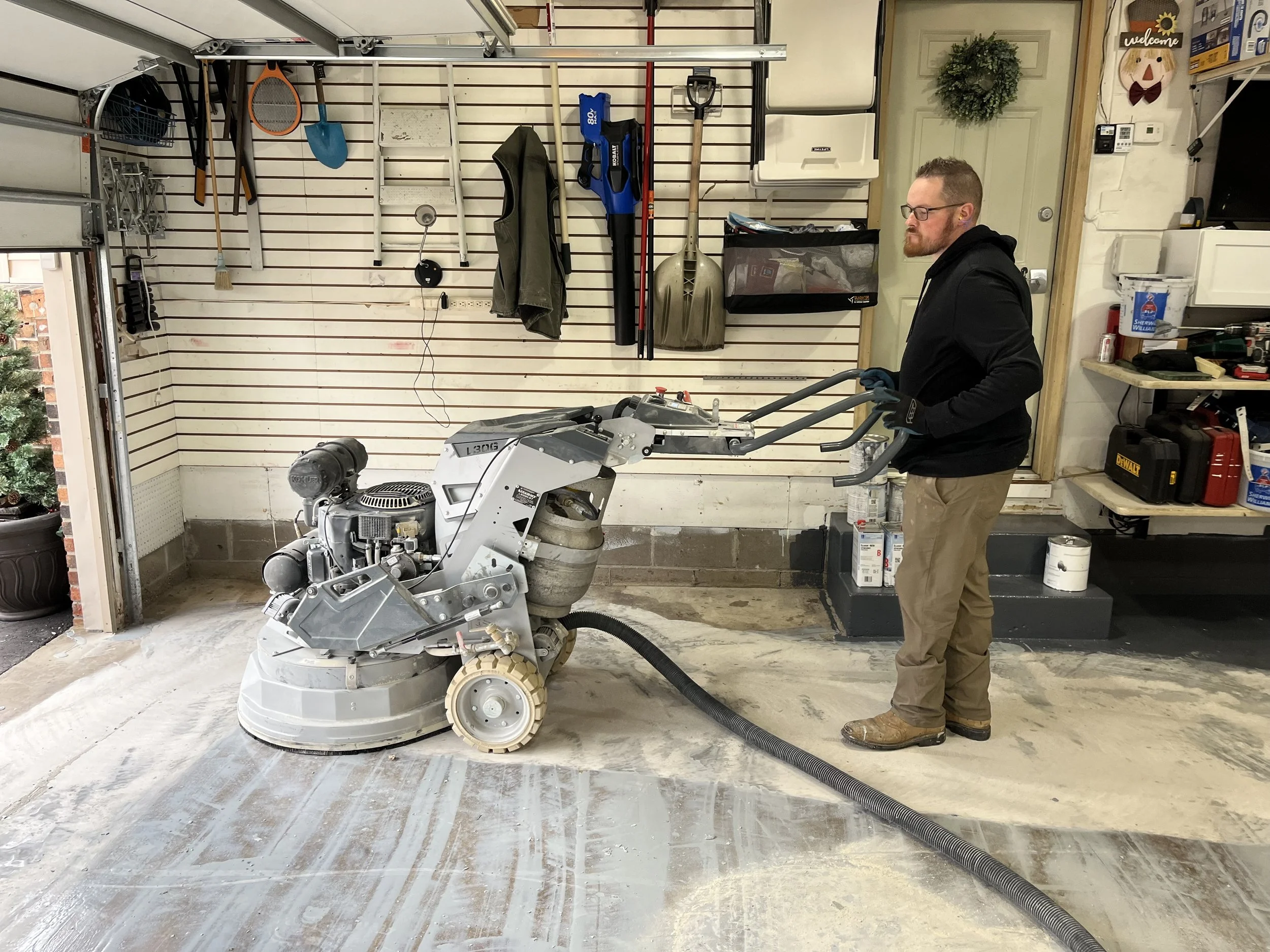 Jesse operating a concrete grinder in a garage, prepping for concrete coating