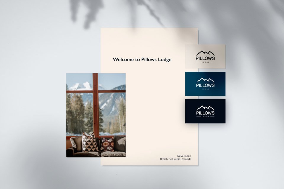 Pillows Lodge welcome sign with a photo of a cozy living room, three sign cards with the lodge's logo, and mentions of Revelstoke, British Columbia, Canada.