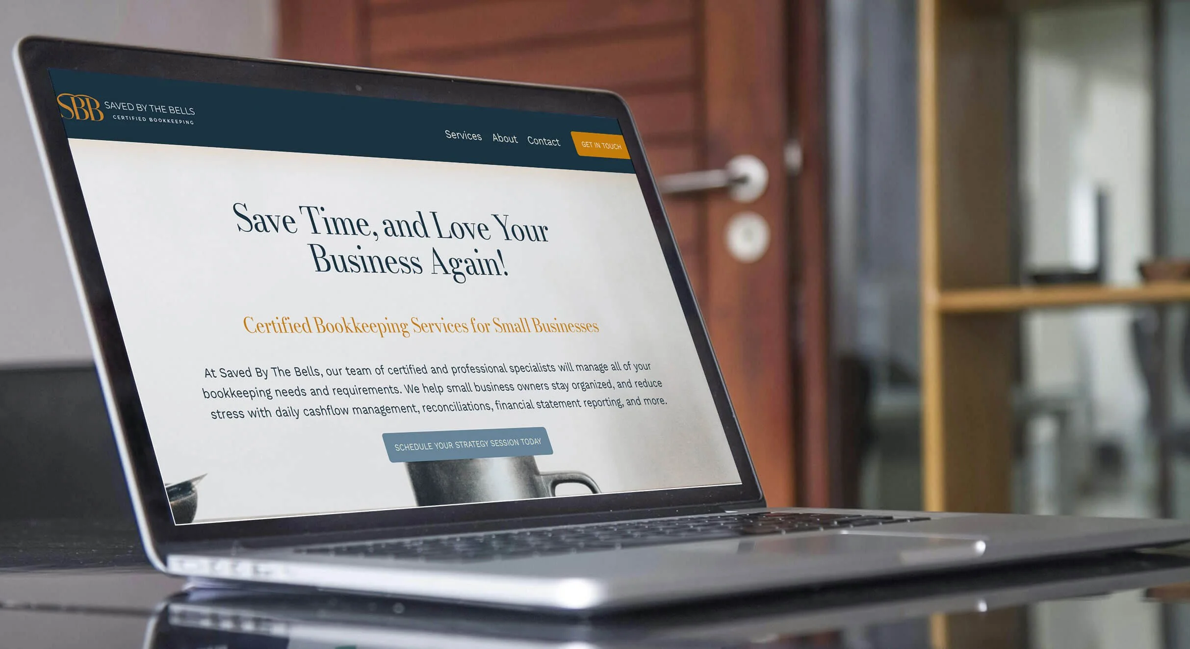 Laptop computer displaying a website for a bookkeeping service called 'Saved By The Bells,' with the headline 'Save Time, and Love Your Business Again!' and a button saying 'Schedule Your Strategy Session Today.'