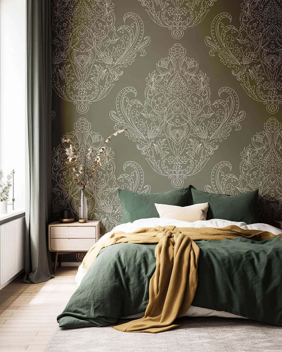 A bedroom with a green bed, beige throw blanket, and white and beige pillows. A nightstand with a vase of dried flowers and a decorative object, next to a window with curtain. The wall behind the bed features intricate white line patterns on a dark g