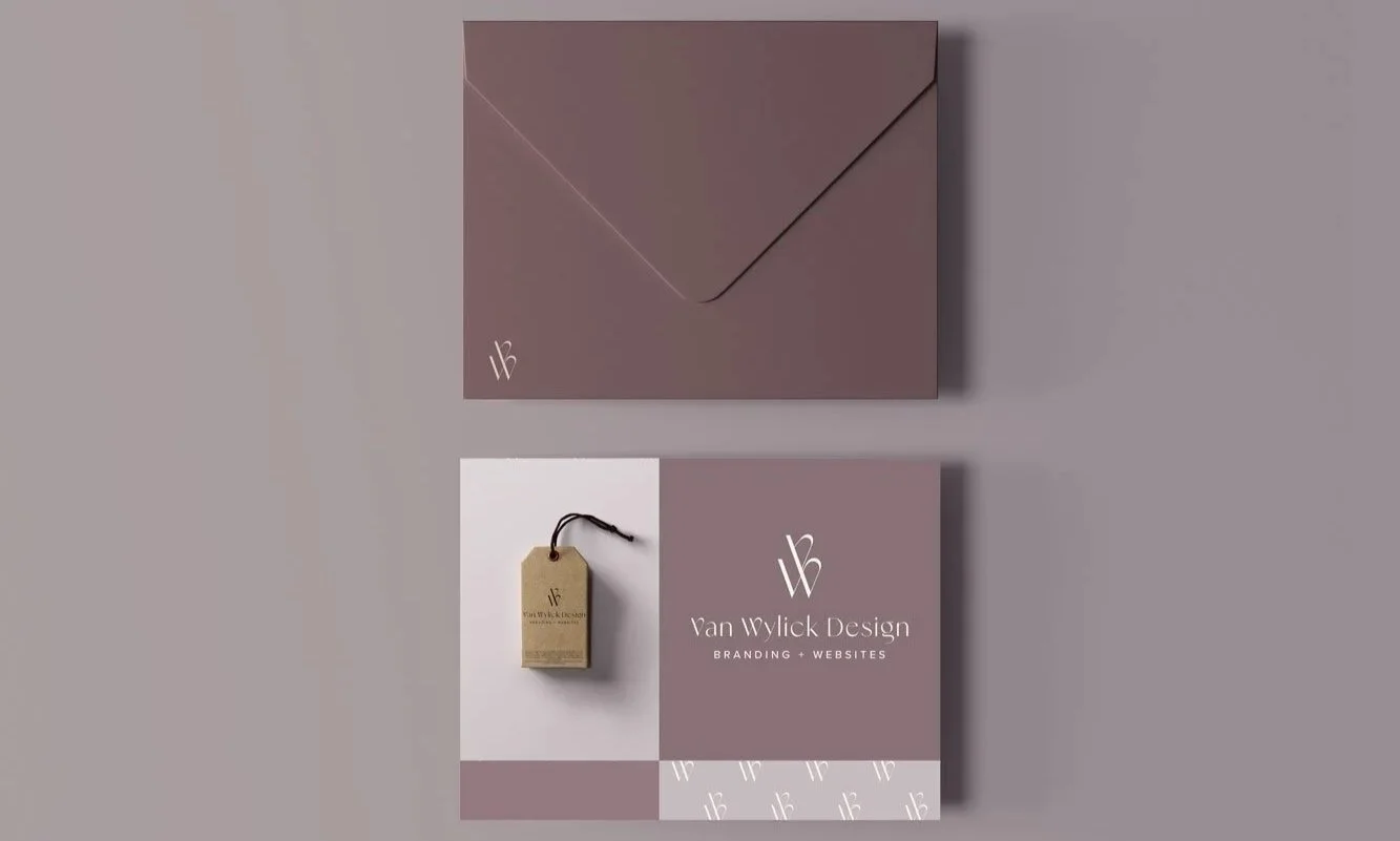 An image showing branding materials for Van Wylick Design, including an envelope and a business card on a grey background. The envelope is brown with a minimalist logo in the lower left corner. The business card has the Van Wylick Design logo and text, accompanied by a small tag on a string.