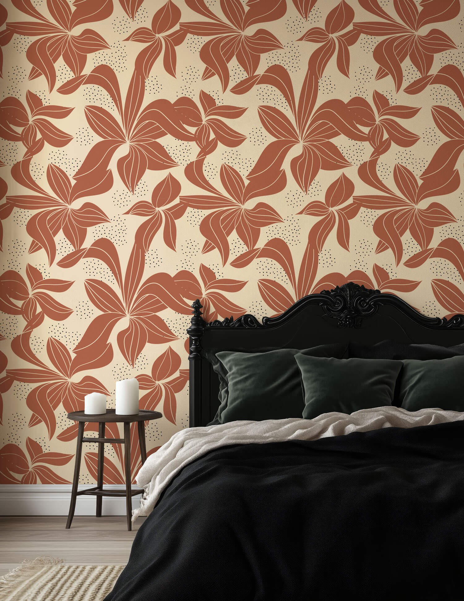 A bedroom with a black bed frame, dark green pillows, beige and black bedding, and a floral wallpaper with large, stylized leaves in shades of brown and cream. A small wooden table beside the bed holds three white candles.