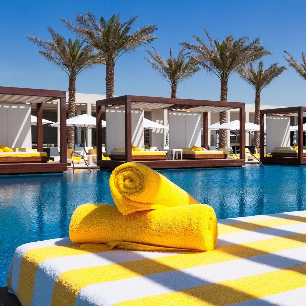 Uma piscina com uma espreguiçadeira e toalhas amarelas