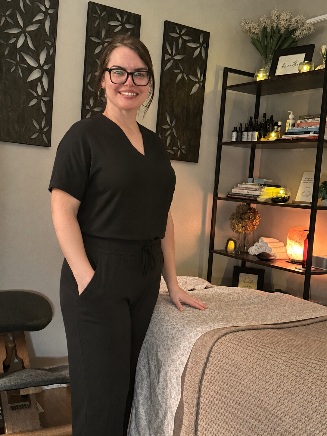 Licensed Massage Therapist Nichole Honeycutt standing beside a massage table in her therapeutic massage office in Durham, NC