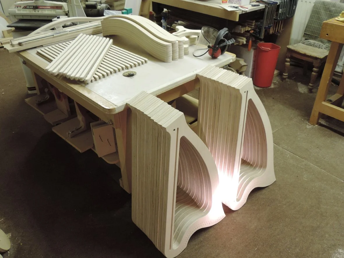 Workshop workspace with partially assembled wooden harps, tools and materials.