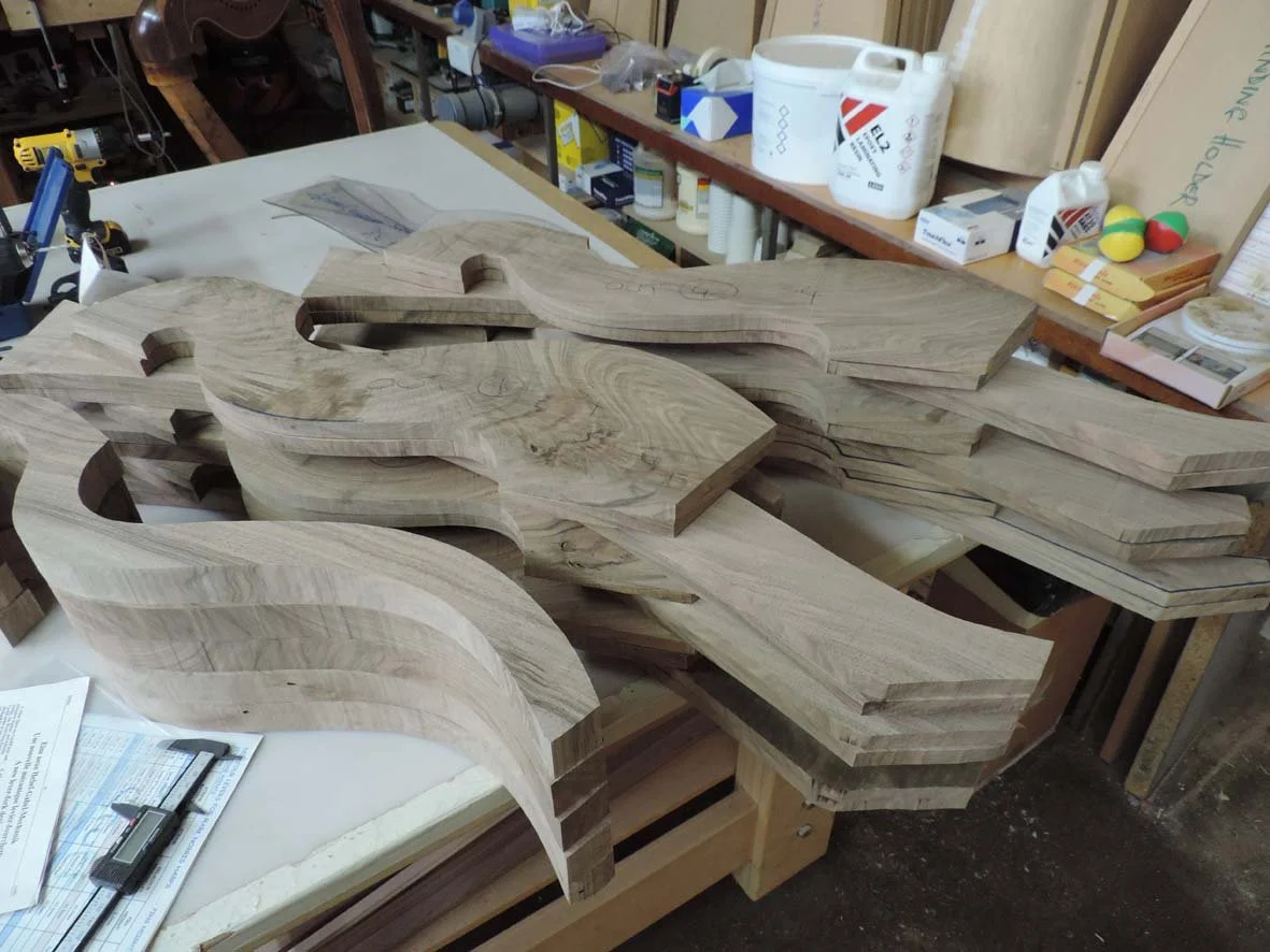 Multiple unfinished wooden harps stacked on a workbench in a workshop.