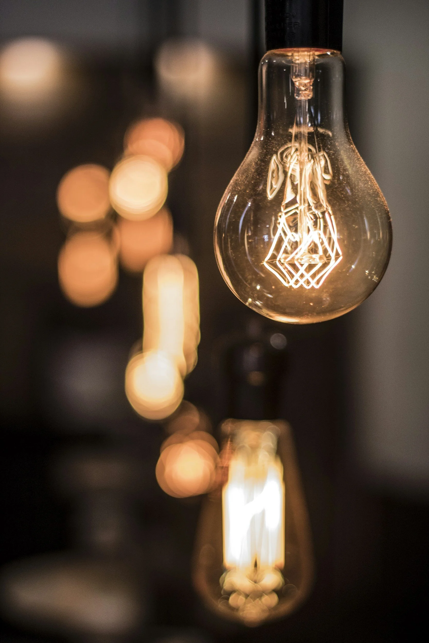 Close-up of illuminated vintage-style Edison light bulbs with exposed filaments, with warm glow and bokeh background.