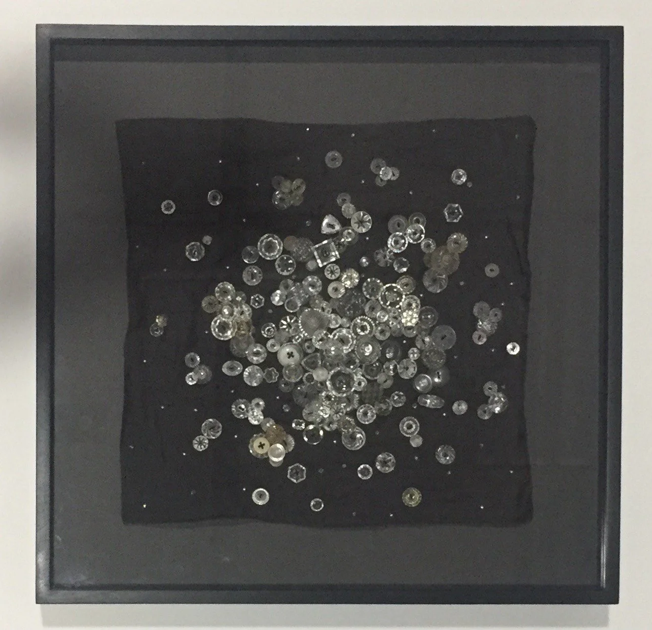 A black display case with clear buttons inside, arranged randomly.