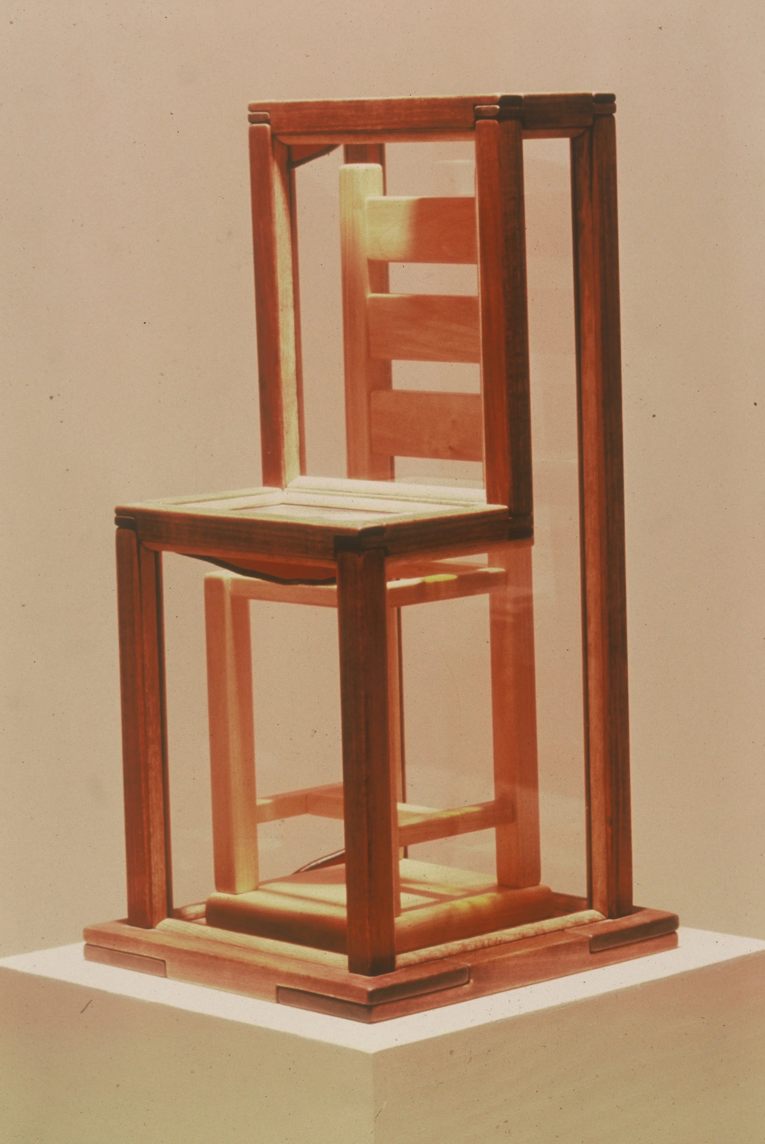 A wooden chair with a tall back and a unique design, displayed on a white pedestal against a plain background.