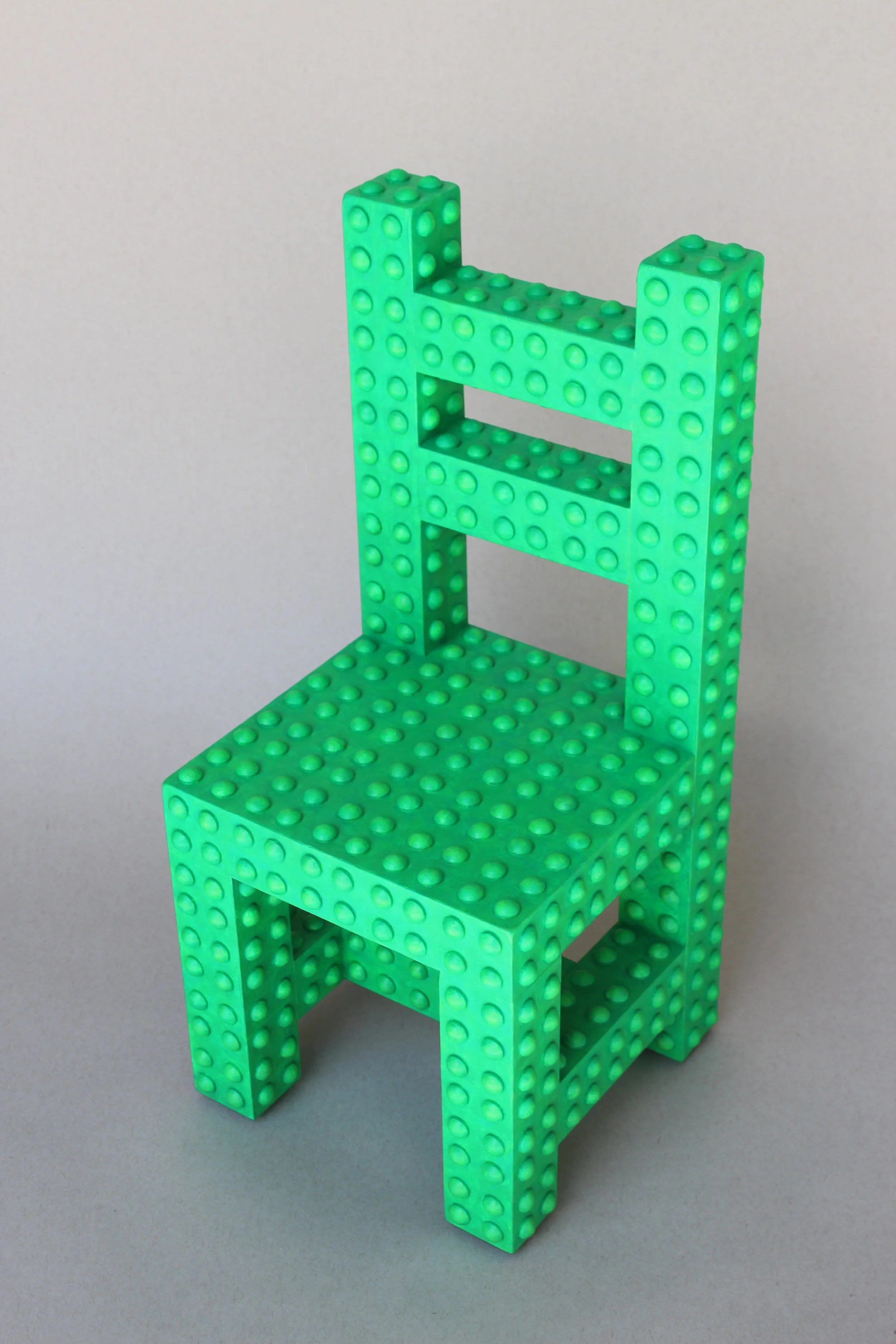 Green LEGO chair with a backrest, set against a plain gray background.