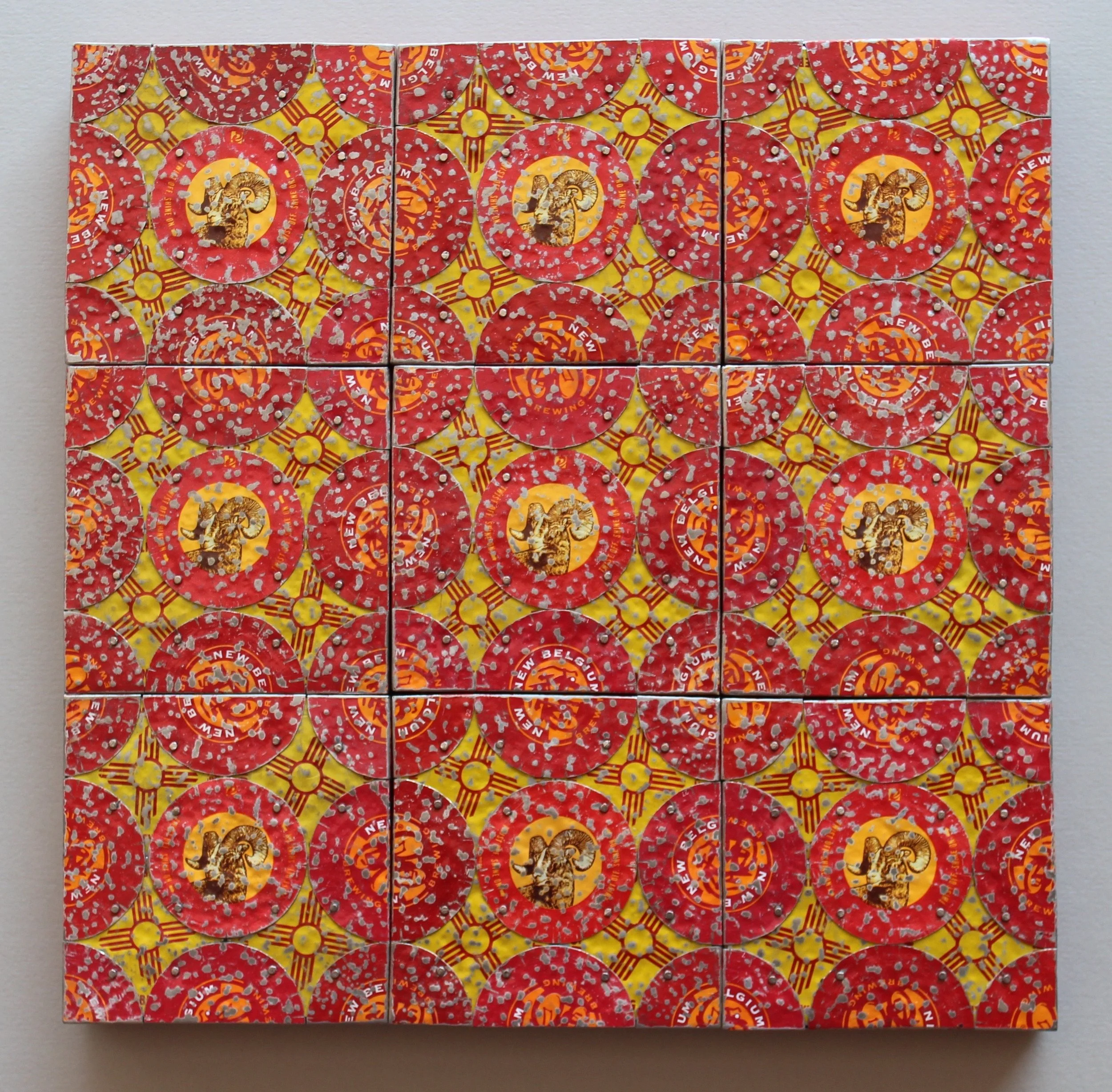 A wall art piece composed of a grid of small, circular, red and yellow beer can pull tabs with a repeating design featuring a lion and some text.