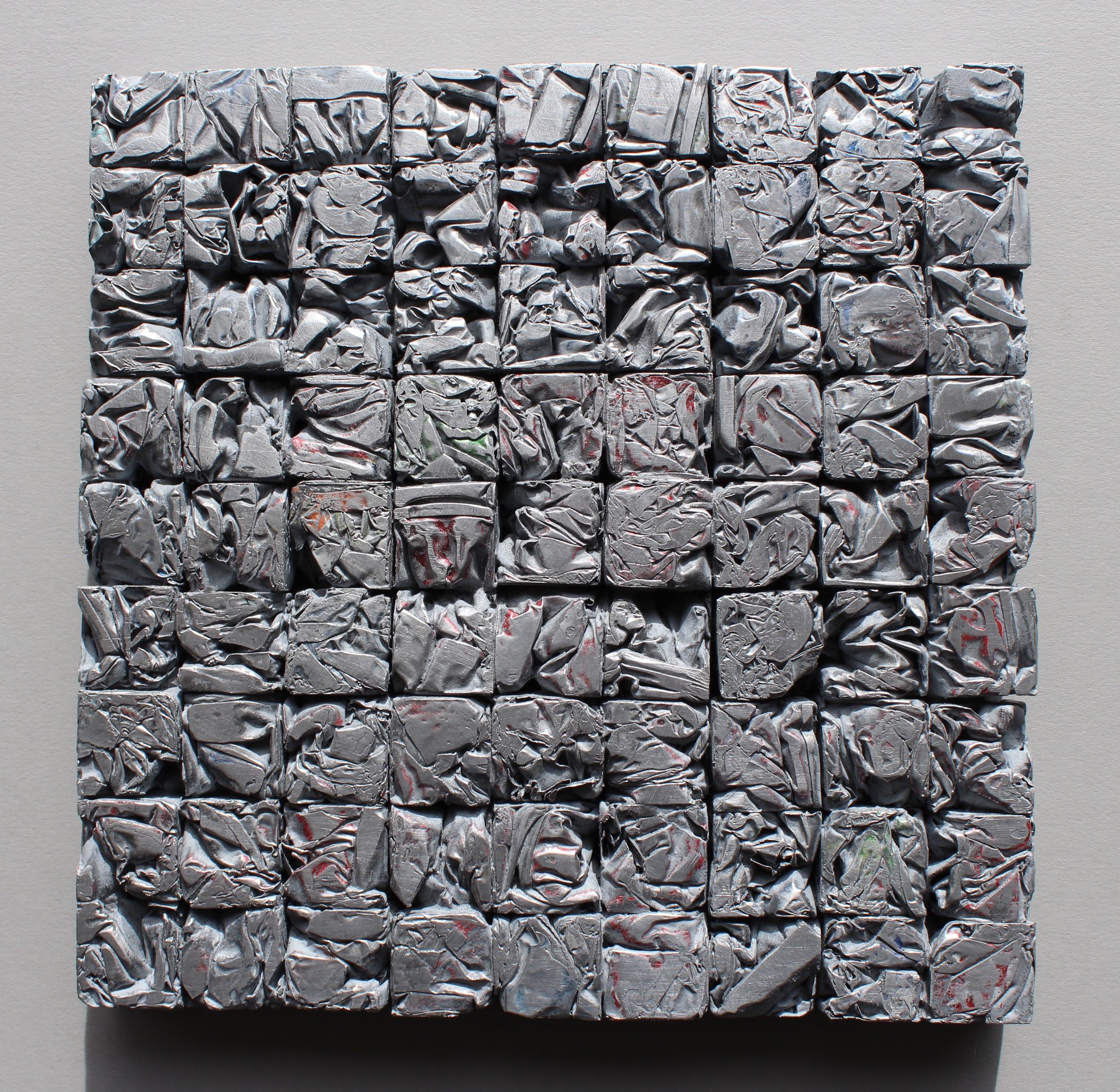 A 6x6 grid of crumpled aluminum foil blocks on a gray background.