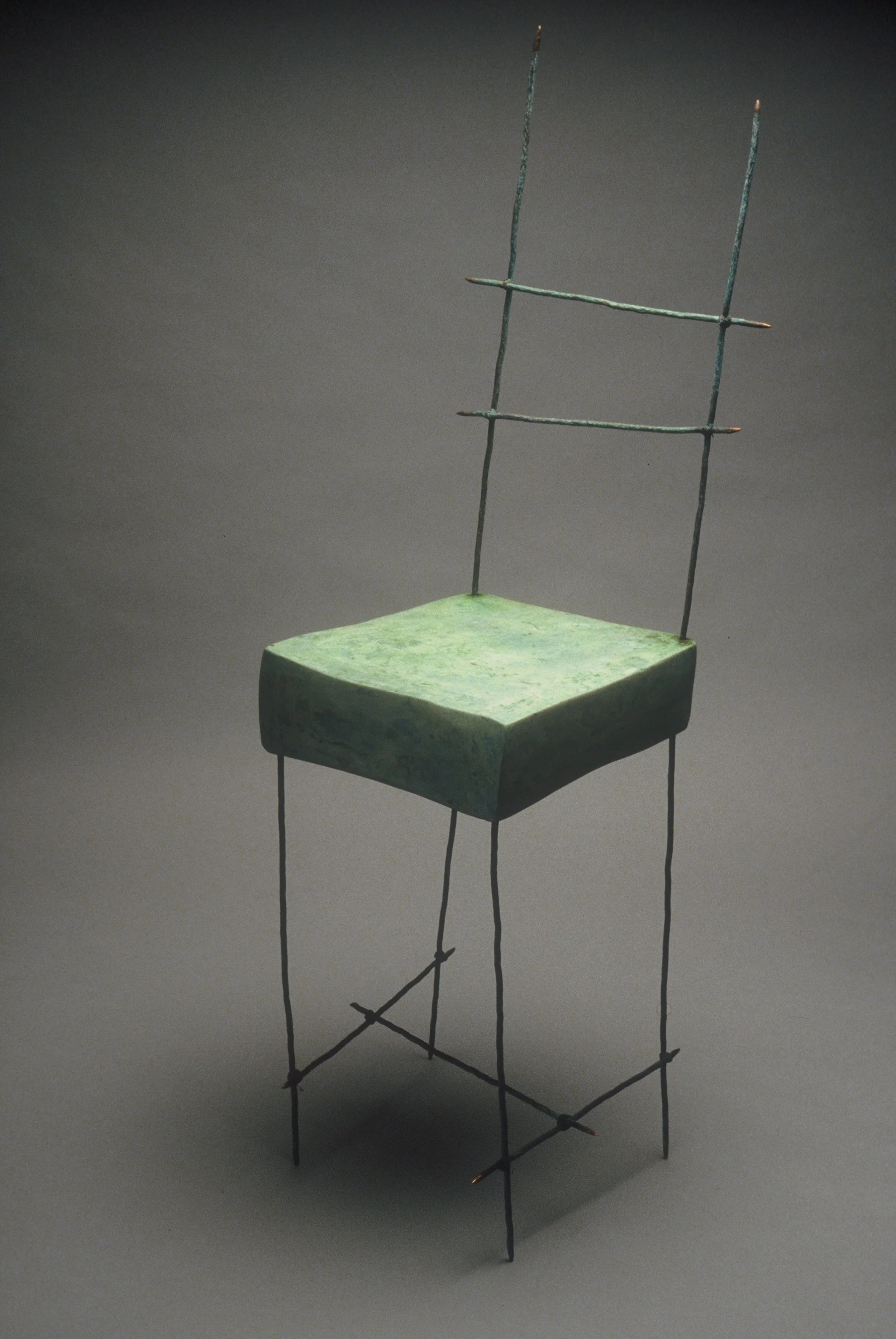 A chair with a square, stone-like seat and thin, metal wireframe support and backrest.