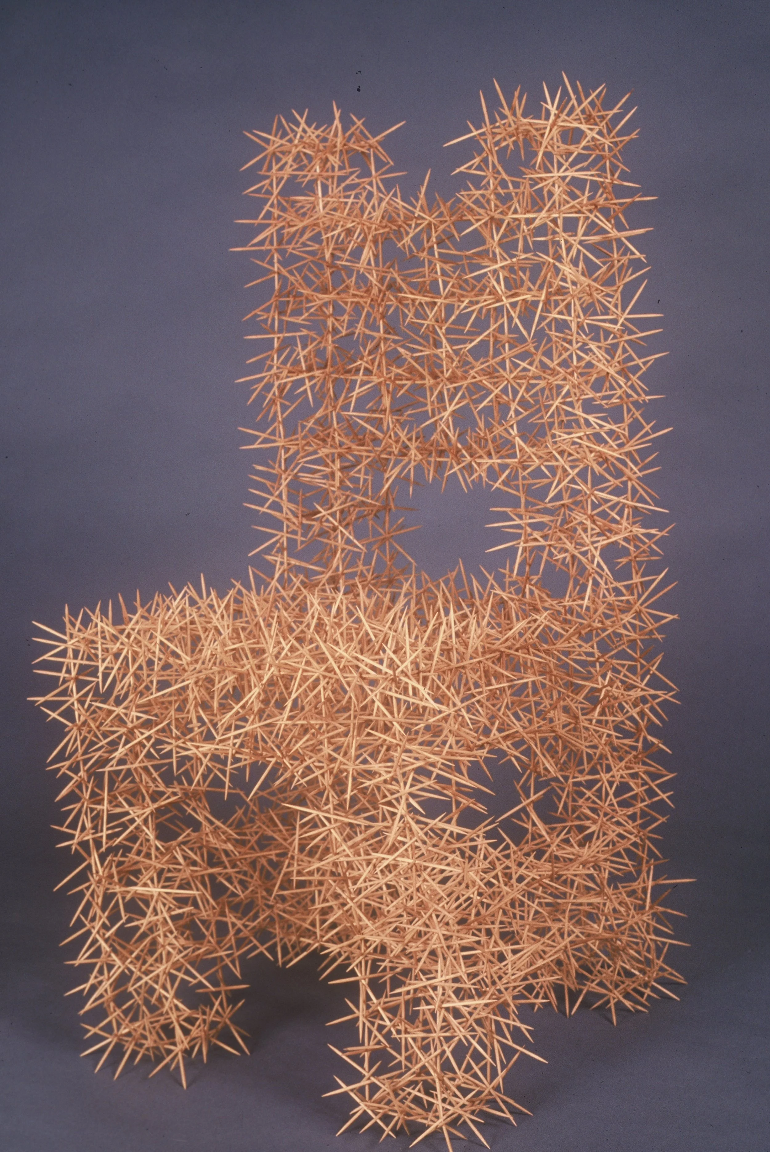 A sculpture made of interwoven wooden sticks resembling a geometric, spiky structure.
