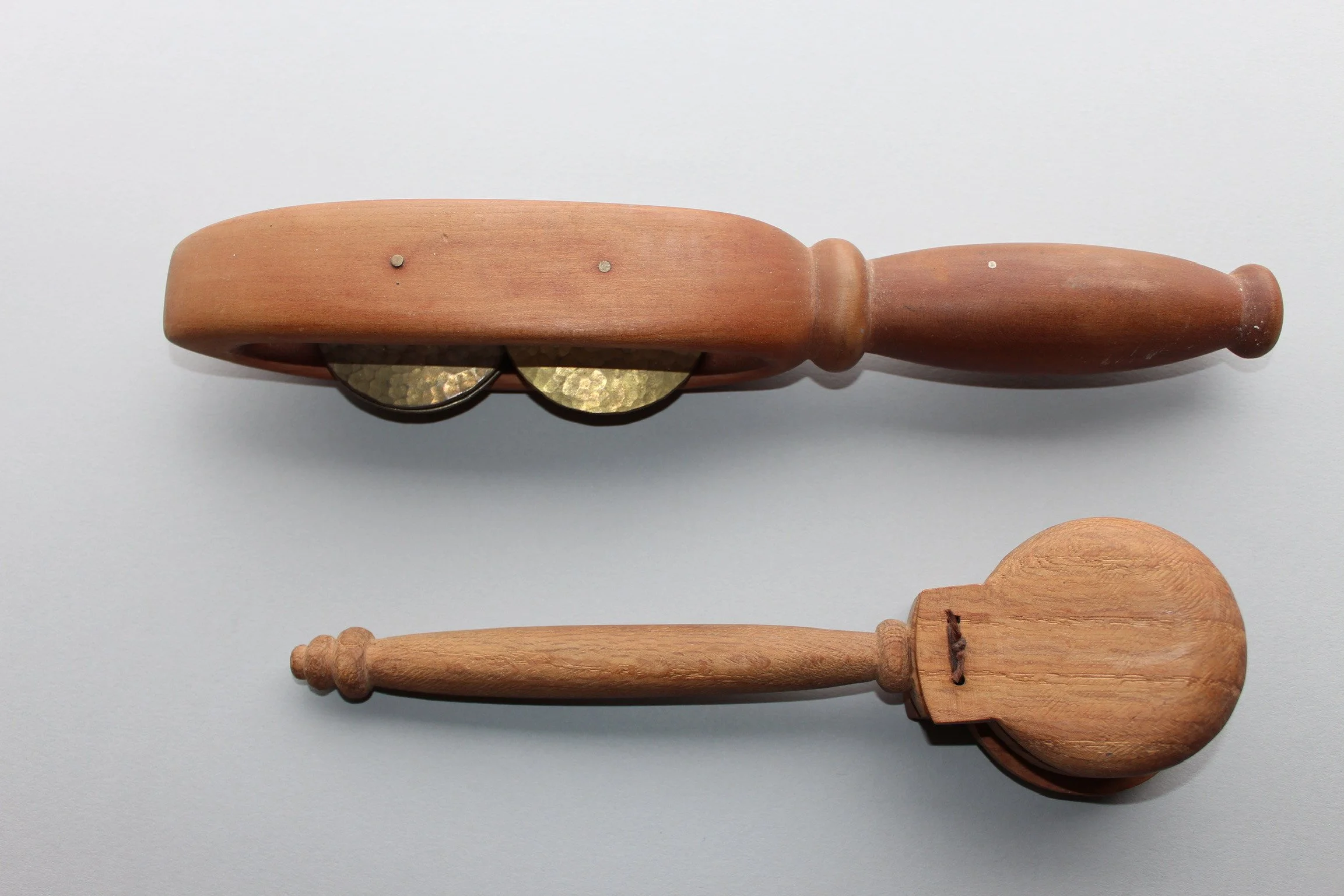 Two wooden kitchen utensils, a pestle and a scoop, on a white surface.