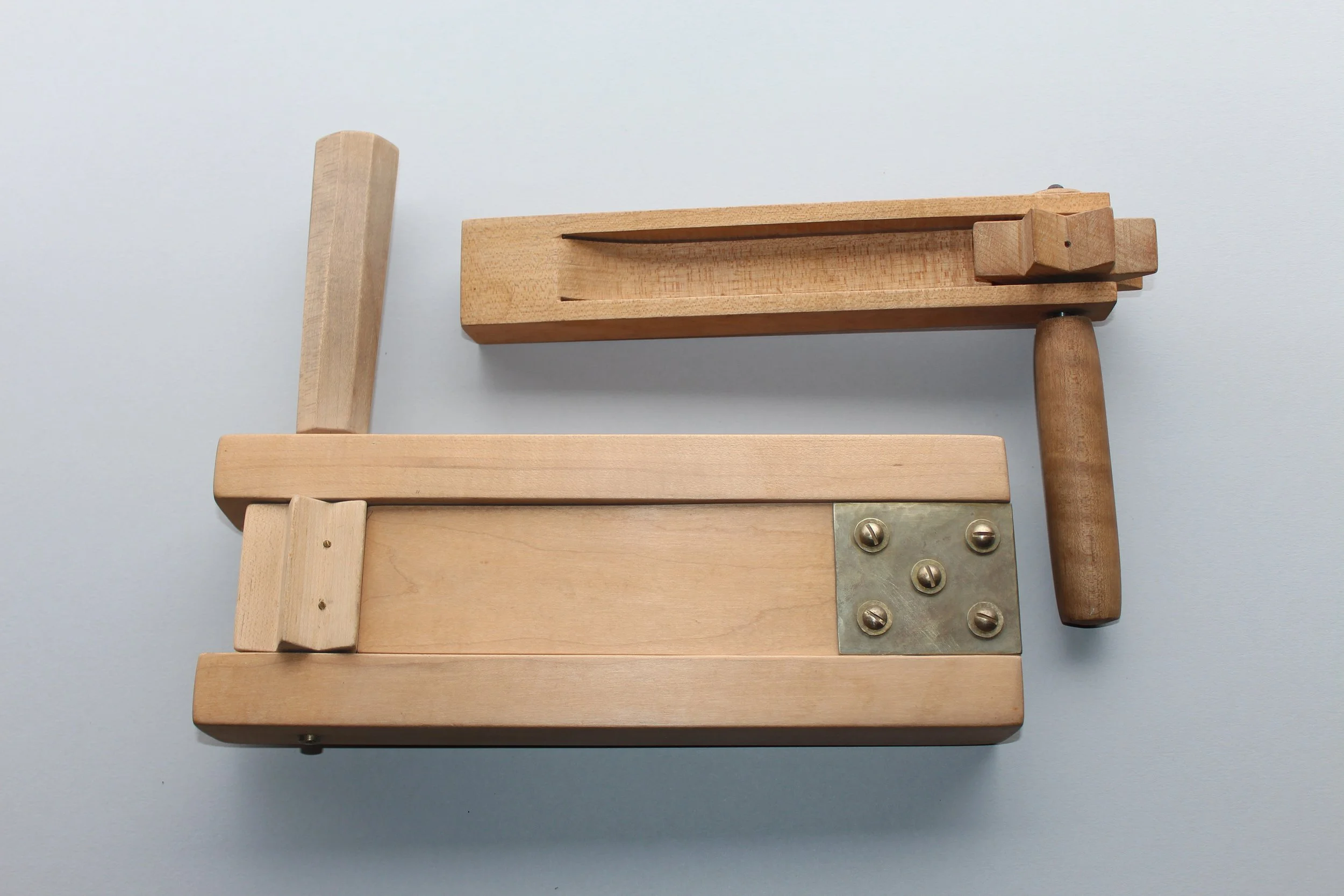 A wooden tool with a metal corner brace and various wooden handles, possibly a woodworking clamp or device.