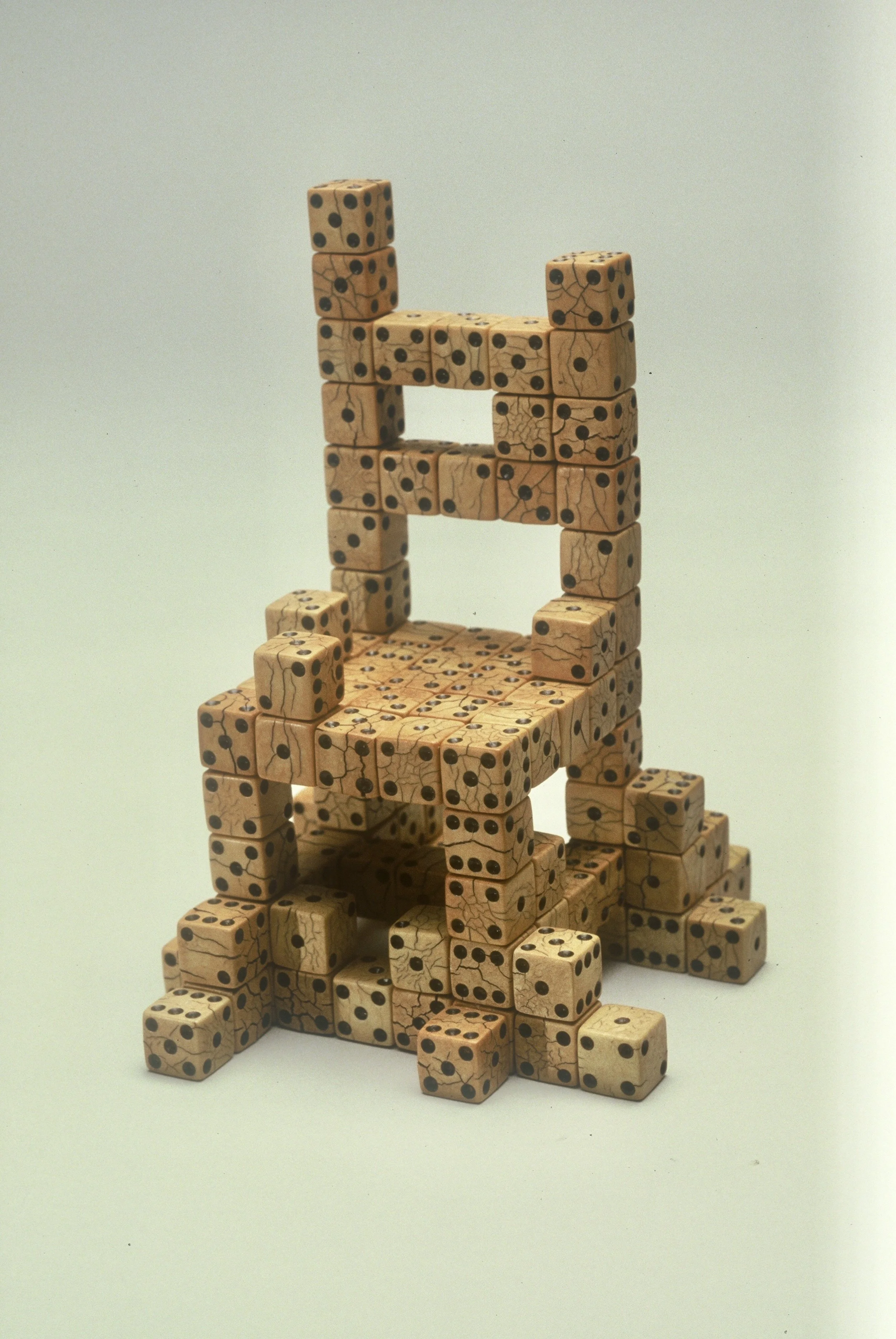 A chair built from multiple beige dice with black dots, arranged in a creative structure.