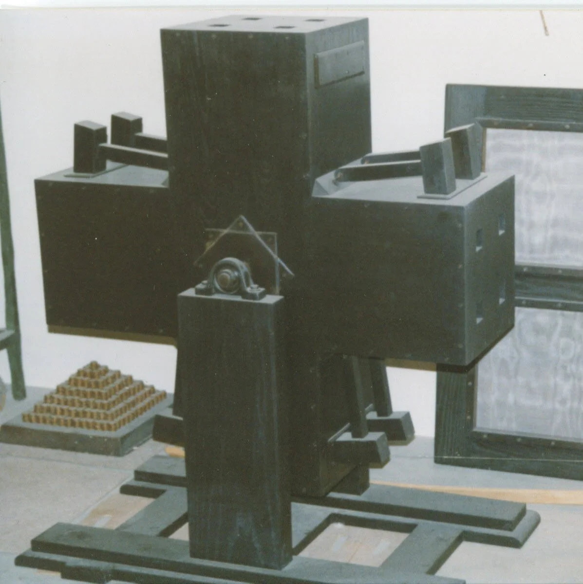 Black vintage mechanical device or machine with various parts and components displayed indoors.