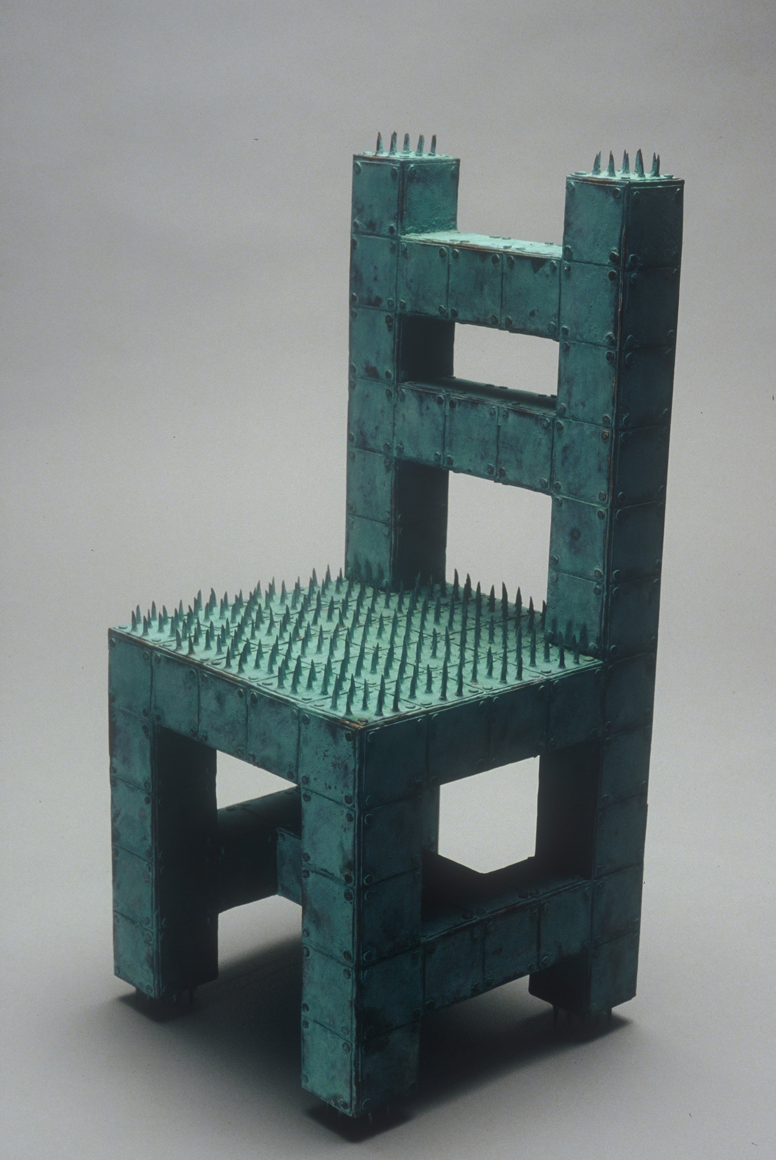 A chair made of metal with spikes on the seat and backrest.