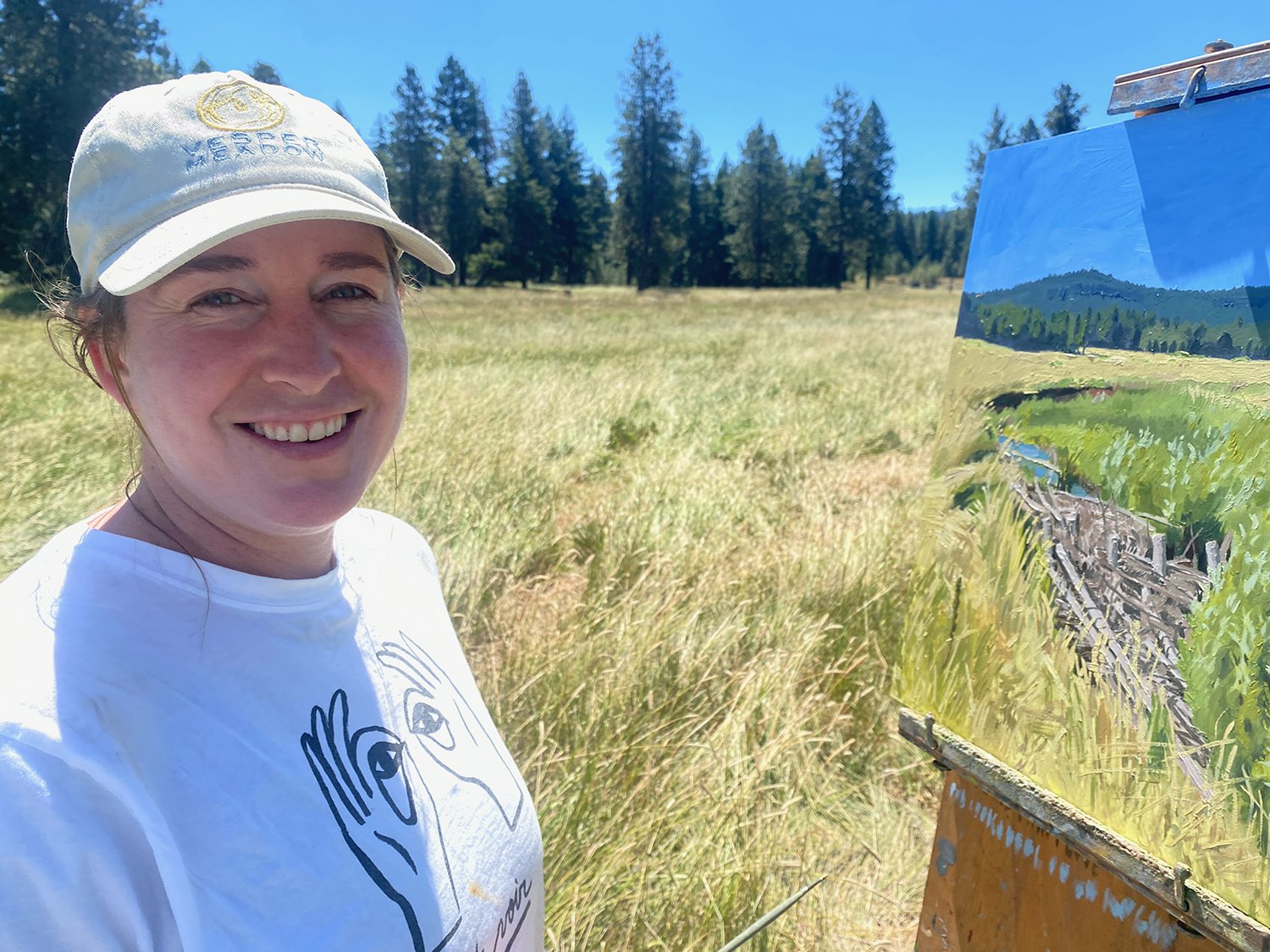 Artist Sarah F Burns with a landscape painting in a Southern Oregon Cascades Meadow.