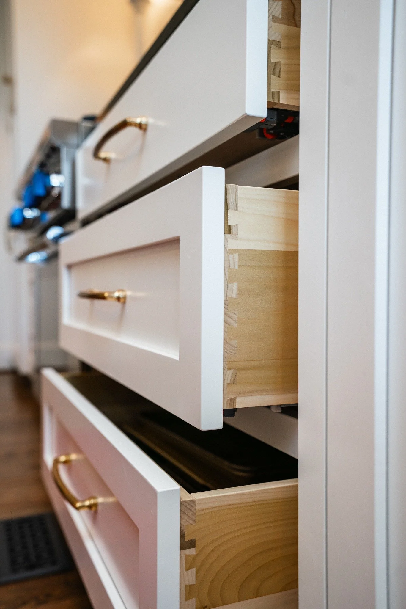 Close-up of a kitchen cabinet with drawers, some of which are partially open, showing unfinished wooden interiors.