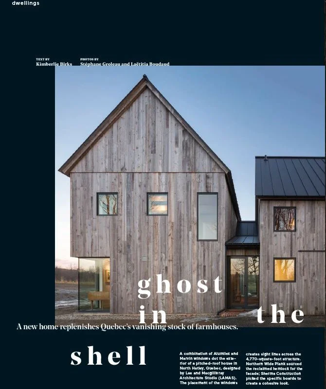 Exterior of a modern farm-style home with wooden siding and multiple windows, set against a dusky sky.