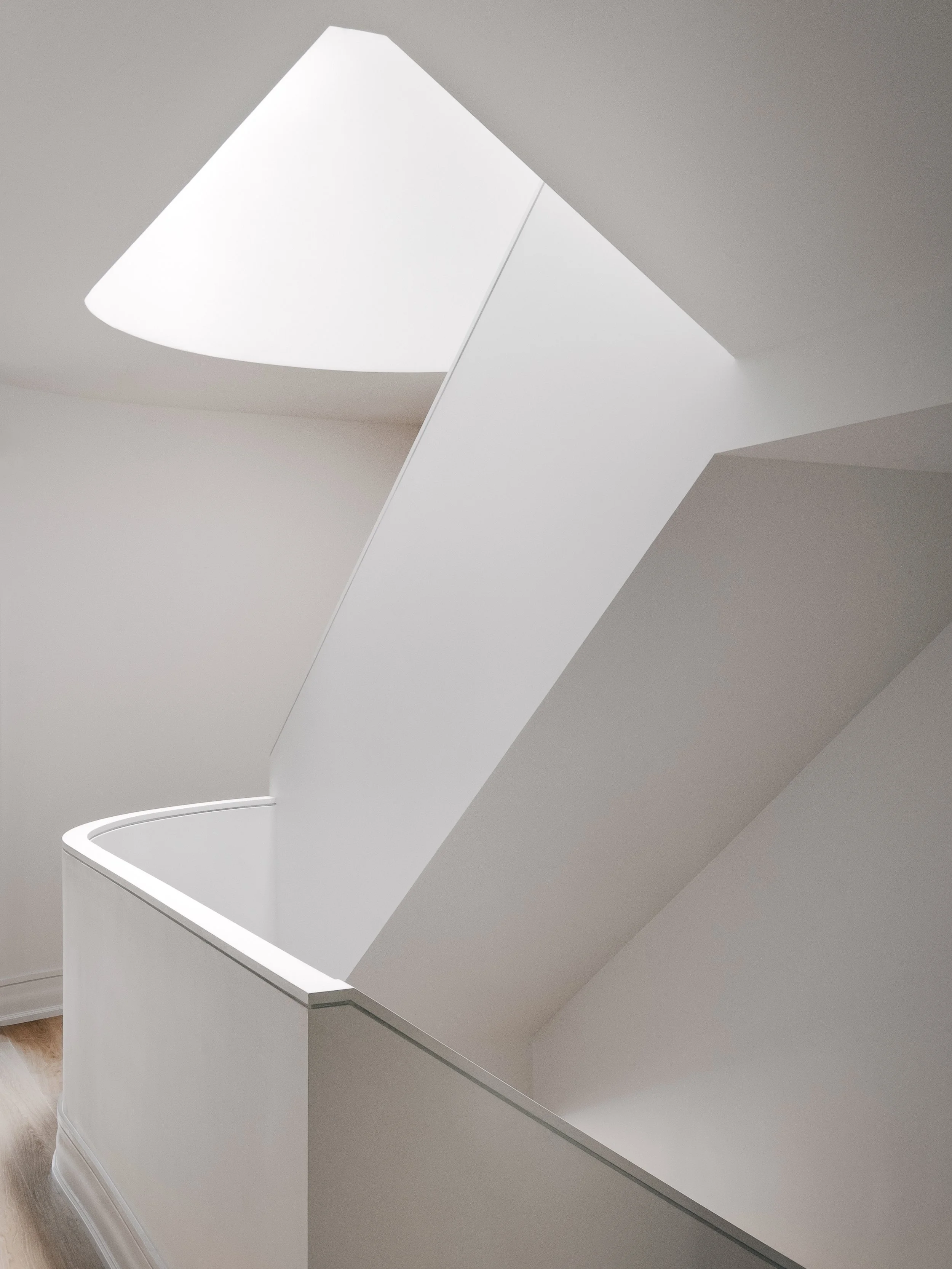 A modern white safe with its lid open, revealing the interior, set against a neutral wall and wooden floor.