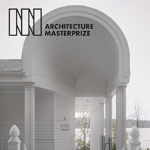 White building with an arched entrance, columns, and a modern design under an overcast sky.