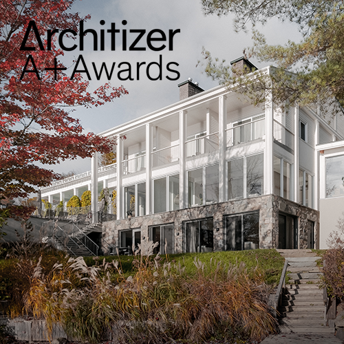 Modern multi-story house with large windows and a deck, surrounded by trees and landscaped yard.