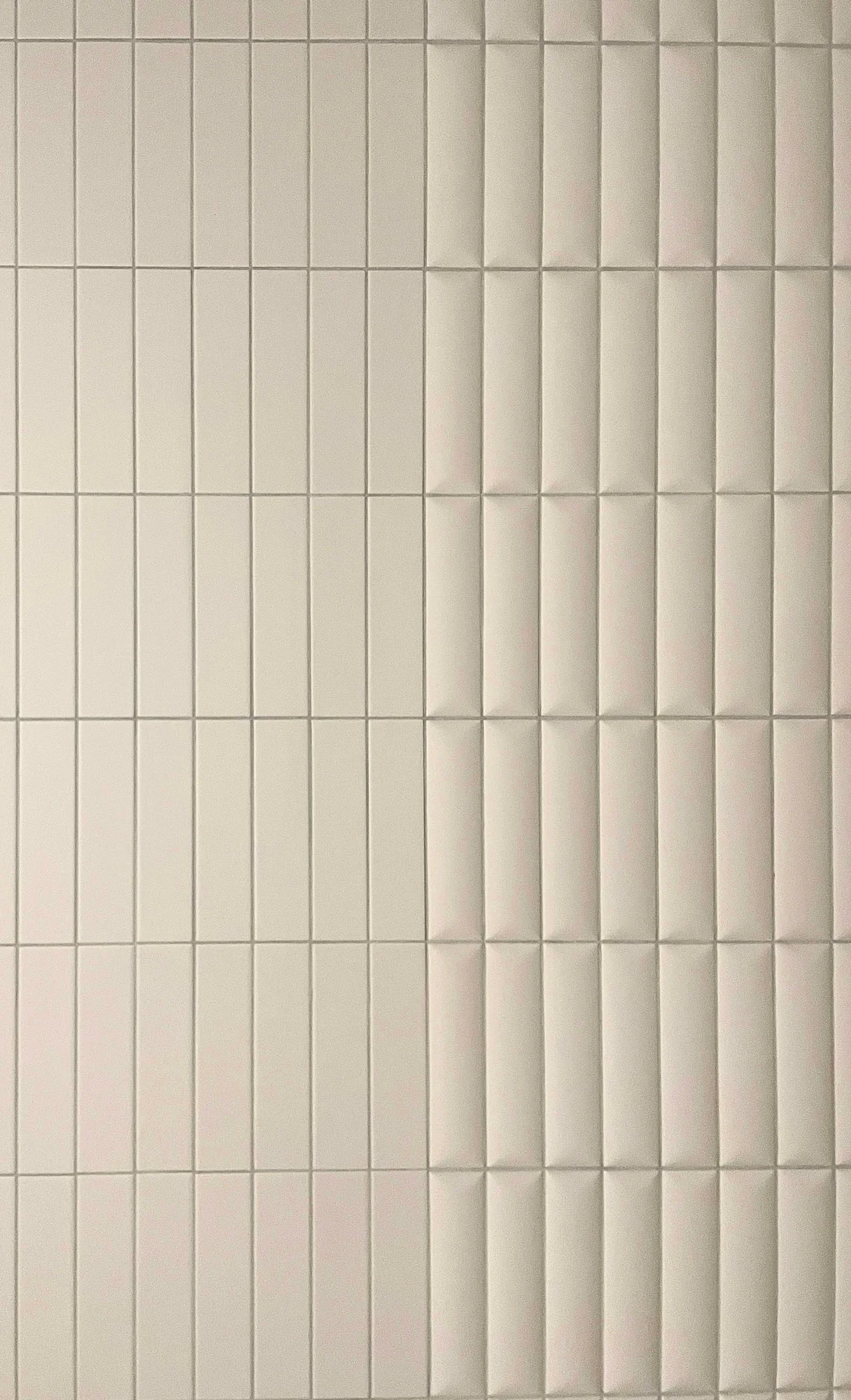 White tiled wall with horizontal and vertical grout lines.
