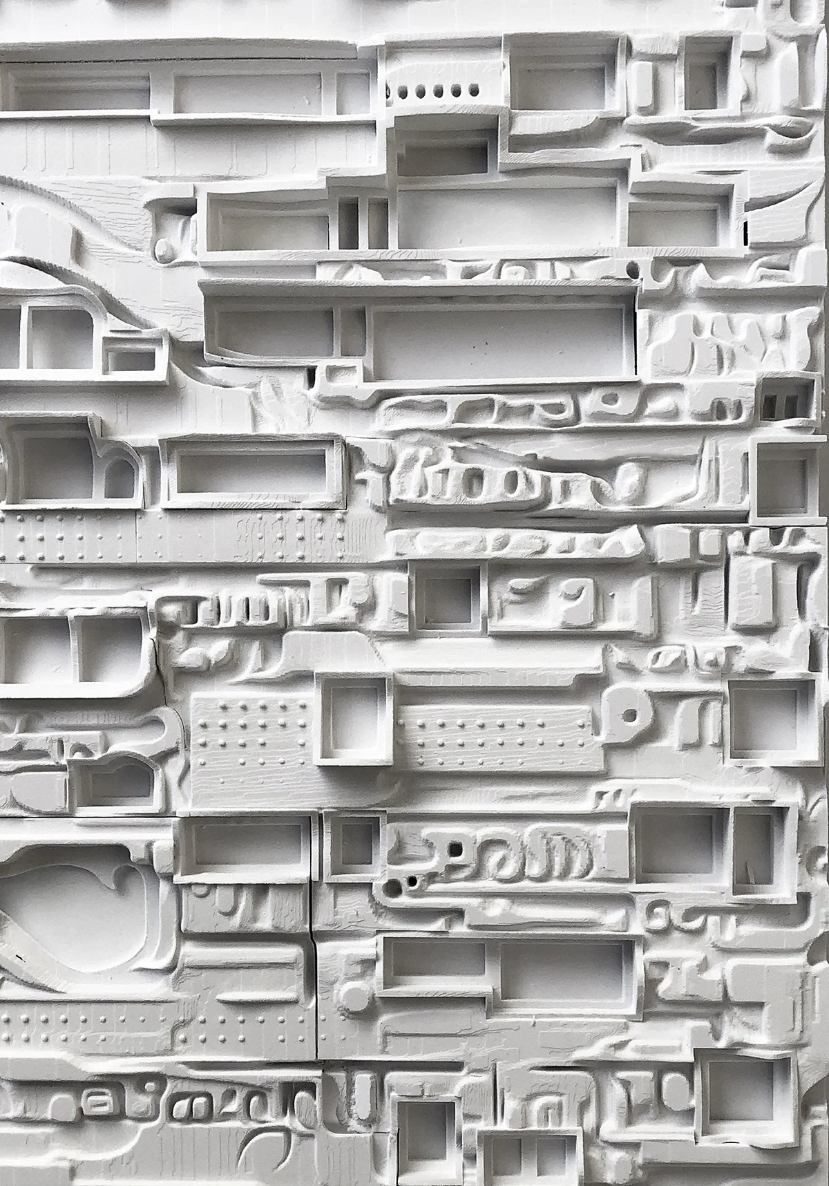 White textured wall with various rectangular and irregularly shaped cutouts and patterns.