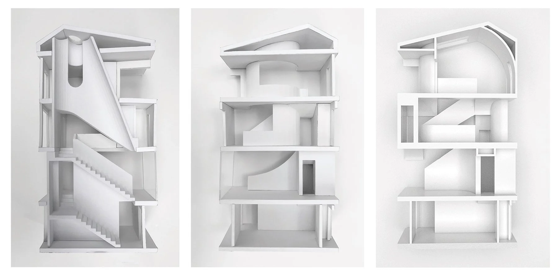 Three white, abstract architectural models with complex interior structures, each shown from a different angle.