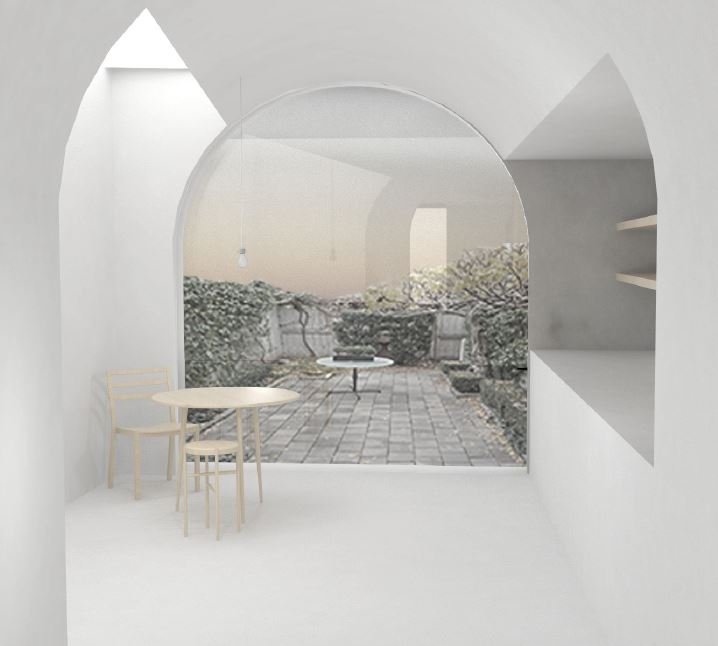 A minimalist room with white walls and furniture, featuring a large window with a view of an outdoor patio with stone paving, benches, and trees.