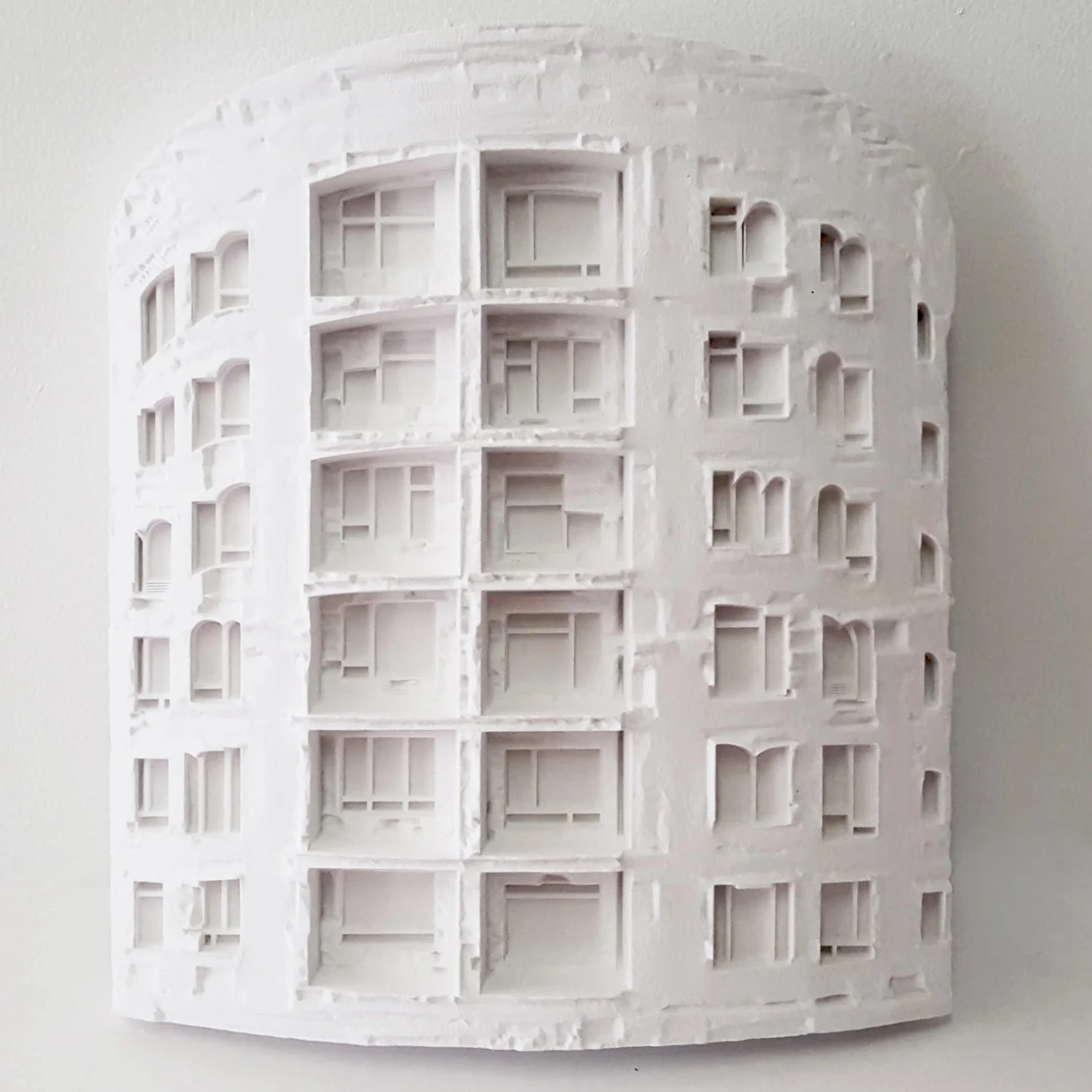 White architectural model of a multi-story building showing open interior spaces, windows, and balconies, viewed from the side.