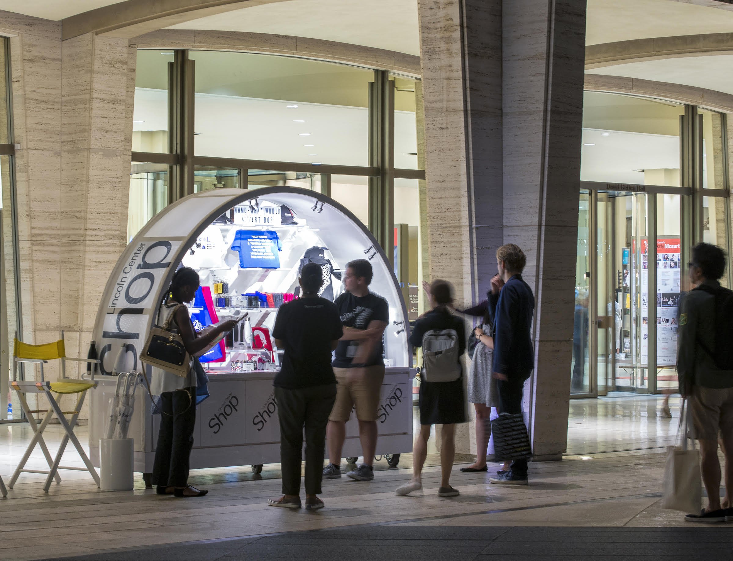 People shopping at a small kiosk inside a shopping mall.