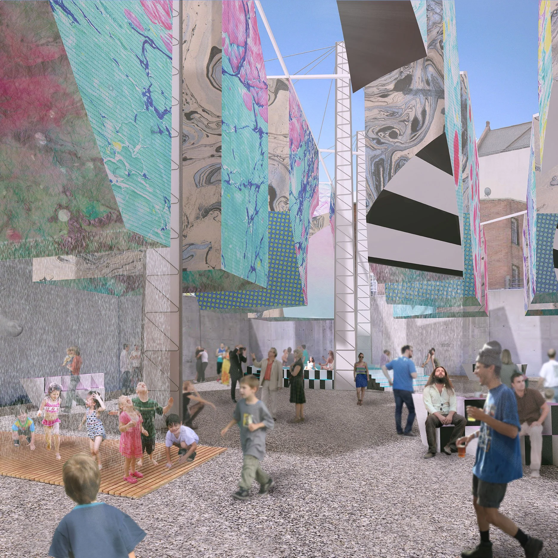 People in an outdoor space with large colorful fabric art installations hanging between tall white structures, children playing on a wooden platform, and adults walking or sitting, with a concrete wall and a building in the background.