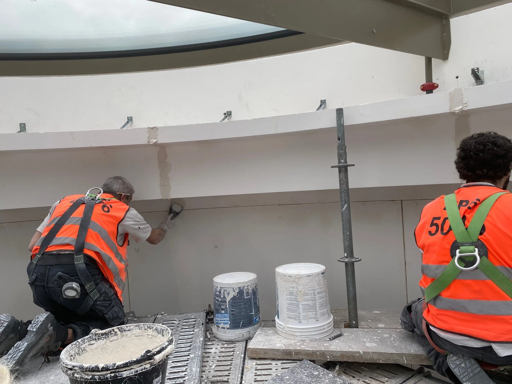 Ouvriers DSD SA appliquant un enduit en plâtre sur une corniche lors d'un chantier de rénovation à Genève